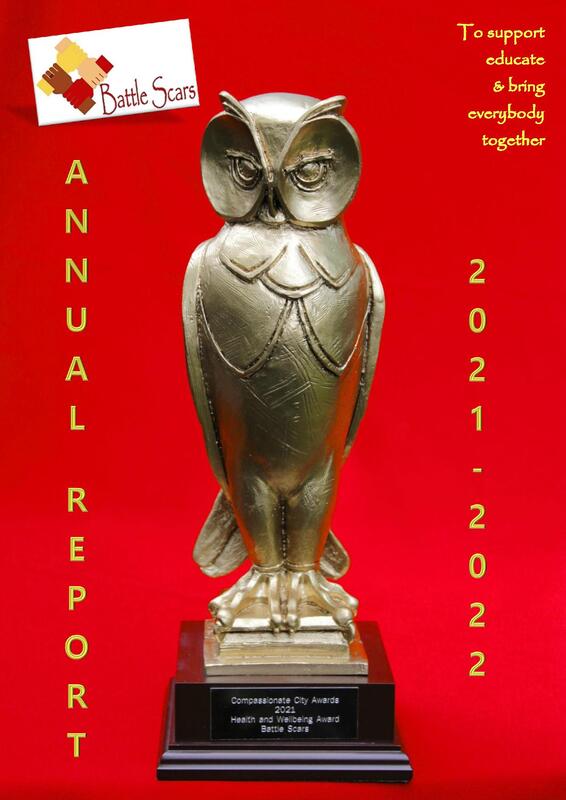Battle Scars annual report 2021-2022 front cover is red with the Compassionate Leeds award which is a gold owl. Links to full report