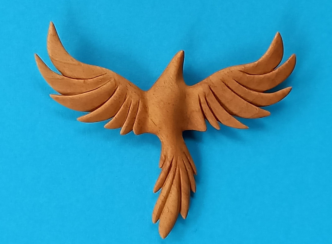 photo of the hand-carved phoenix in light wood and blue background