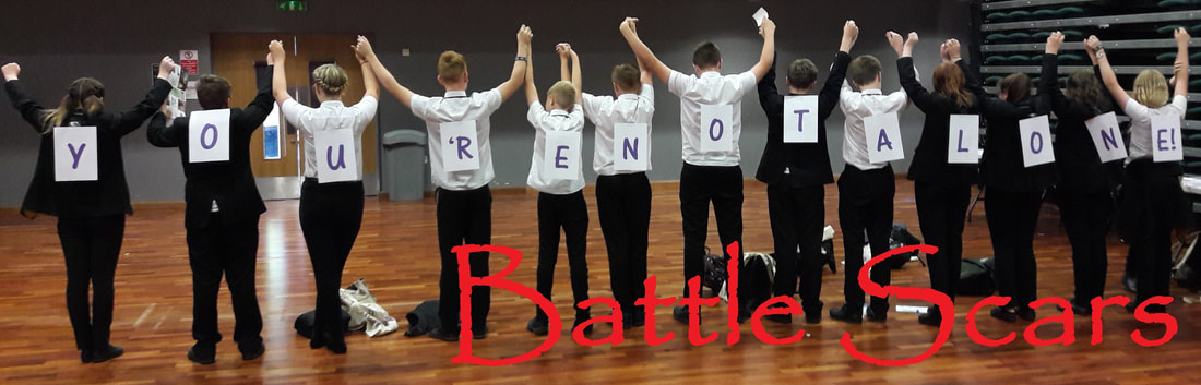 13 young people facing away holding hands with letters on their backs spelling you're not alone